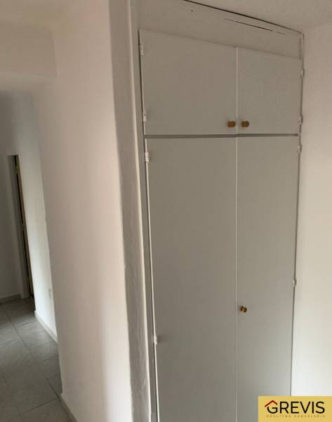 White built-in storage in the hallway, 2-room apartment, simple tiles on the floor.