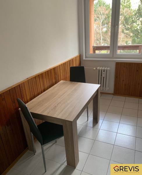 Dining nook with a wooden table and two chairs by the window in a 2-room apartment.