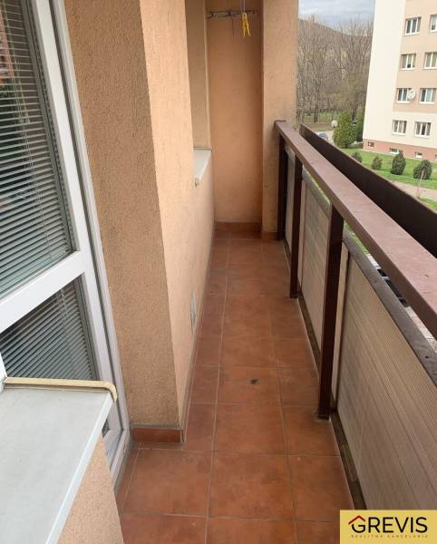 A balcony in a 2-room apartment with tiles and glass doors.