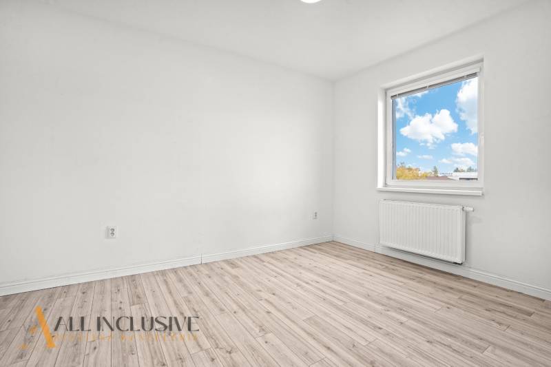 A bright room with wood-decor flooring and a window in a two-room apartment.