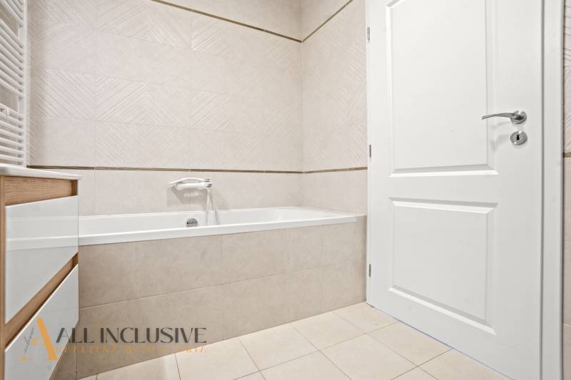 Bathroom with a bathtub, white doors, and light tiles in a 2-room apartment.