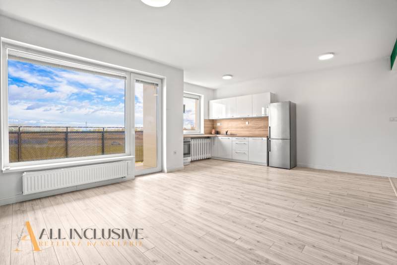 A bright interior of a 2-room apartment with a kitchen, a glass wall, and a floor with a wooden decor.
