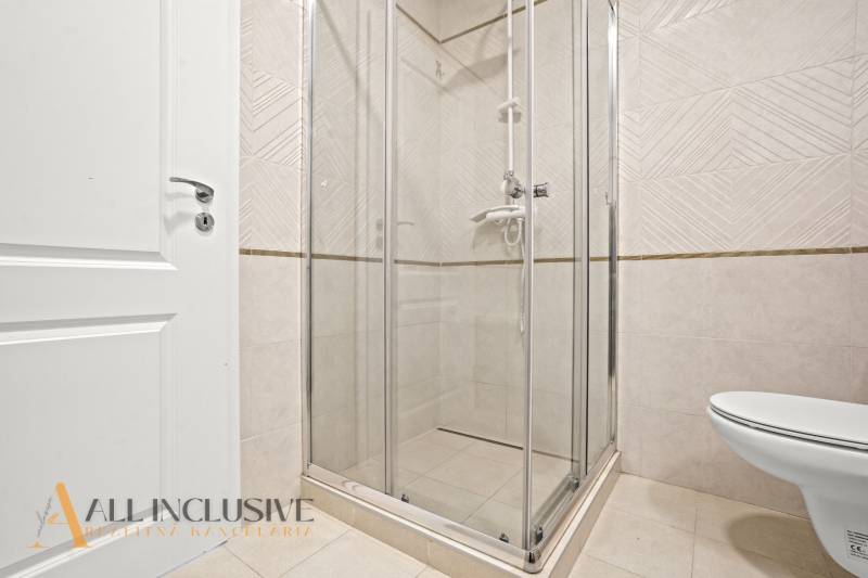 A bathroom with a glass shower enclosure and tiles in a 2-room apartment.