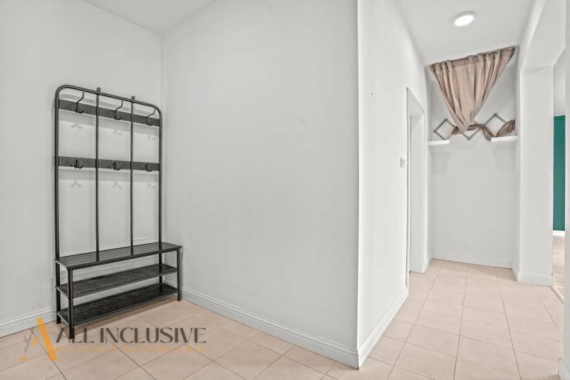 A hallway in a 2-room apartment with a wall-mounted coat rack and tiled flooring.
