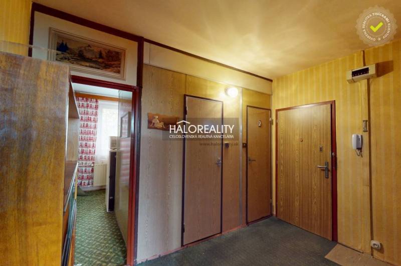 An entrance hallway in a 3-room apartment with wooden decoration and a patterned carpet.
