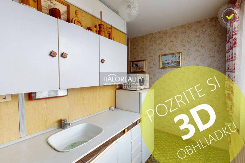 A kitchen in a 3-room apartment with white cabinets and pictures on the walls.