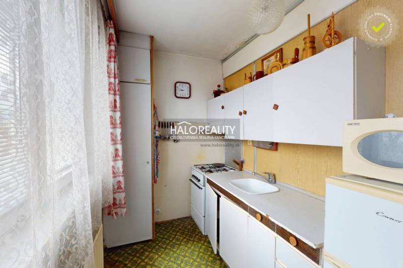 A kitchen in a 3-room apartment with a white cabinet, a gas stove, and vintage decorations.