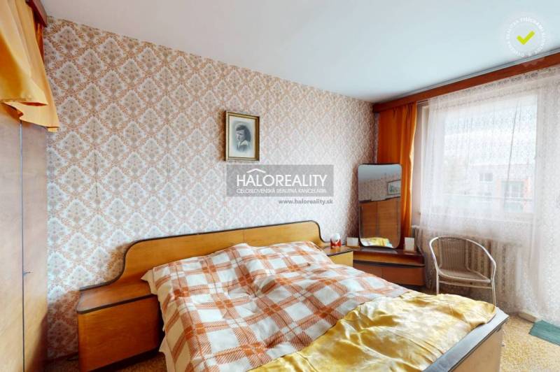A bedroom in a 3-room apartment with patterned wallpaper and wooden details on the furniture.