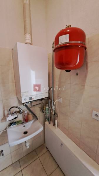 Gas boiler with a sink in commercial premises, tiled floor, walls covered with tiles.