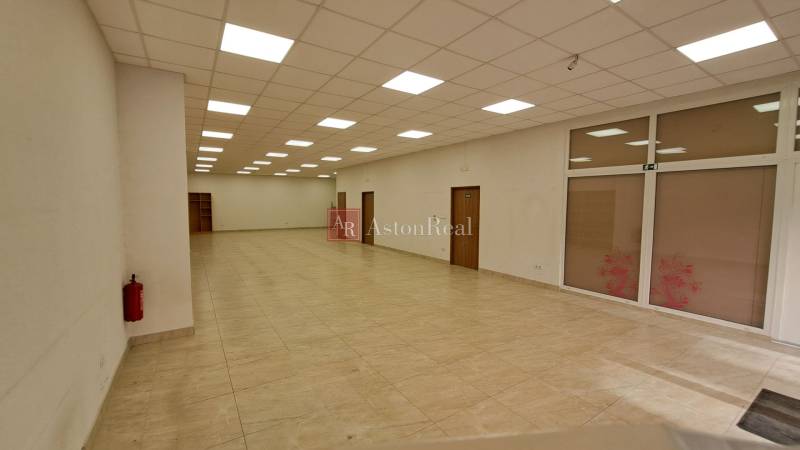 Space with tiles, ceiling lights, and doors in commercial premises.