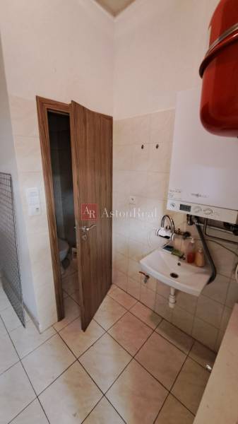 Bathroom in commercial premises with a sink, boiler, and door to the toilet.