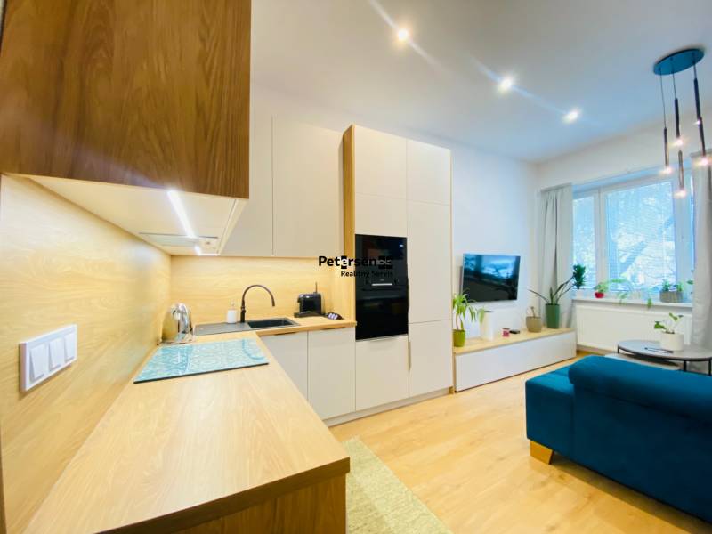A kitchen unit with a wooden decor in a 2-room apartment with a bright living room.