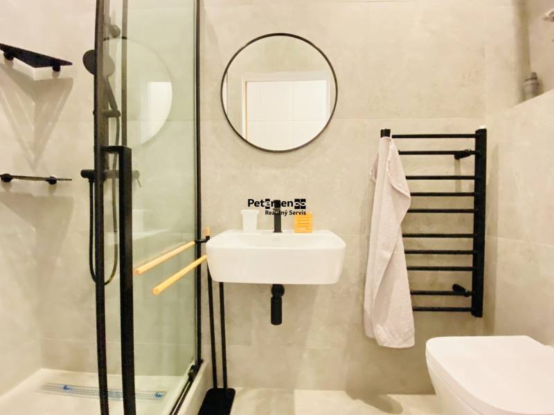 Bathroom in a 2-room apartment with a shower, mirror, and towel rack.