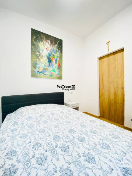 Bedroom with a painting on the wall, a bed, and a nightstand in a two-room apartment.