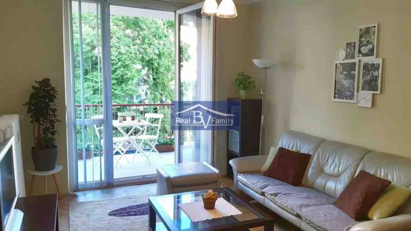 Living room in a 2-room apartment with a spacious balcony and a view of greenery.