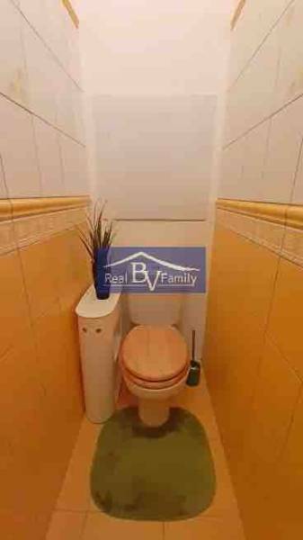 A toilet with beige walls and tiles in a 2-room apartment with decoration.