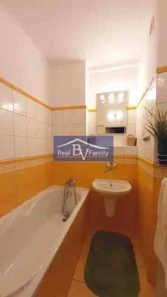 A bathroom in a 2-room apartment with tiles in warm shades and a bathtub.