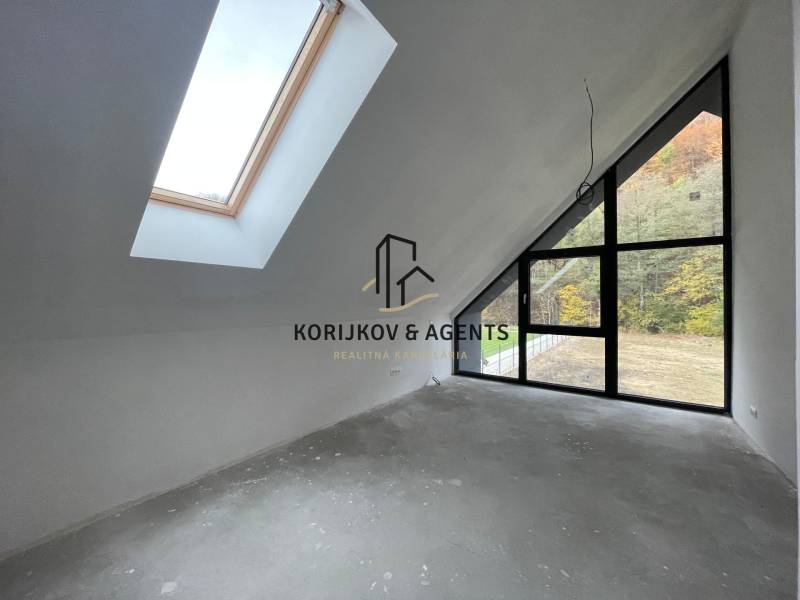 An attic room in a family house with large windows and a view of the forest.
