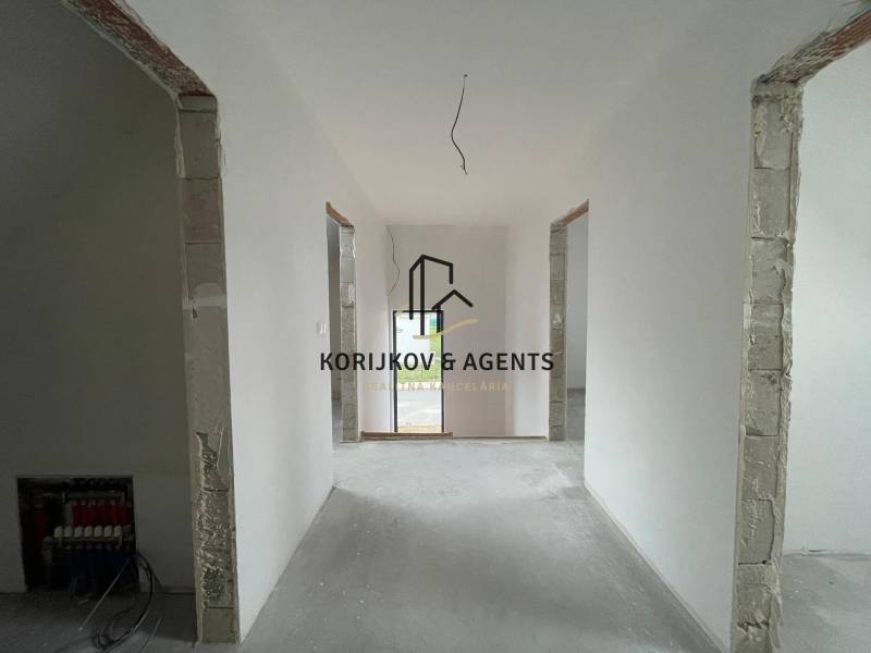 The interior of a family house with white walls and open doors to another room.