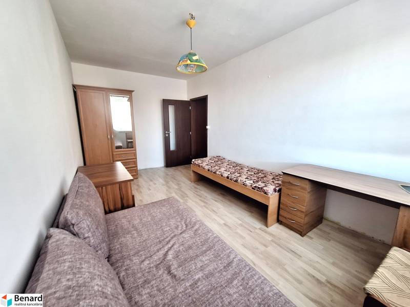 A room in a 3-room apartment with a wooden-decor floor, a bed, and a wardrobe.