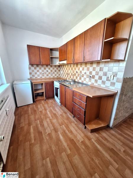 A kitchen in a 3-room apartment with a wooden decor floor and wooden cabinets.