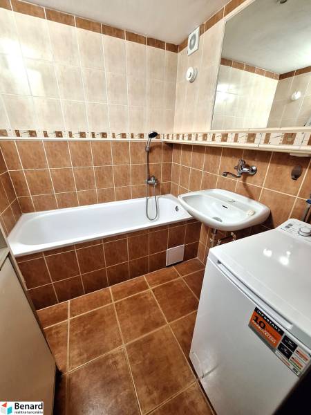 Bathroom with a bathtub in a 3-room apartment, brown tiles, sink, and washing machine.