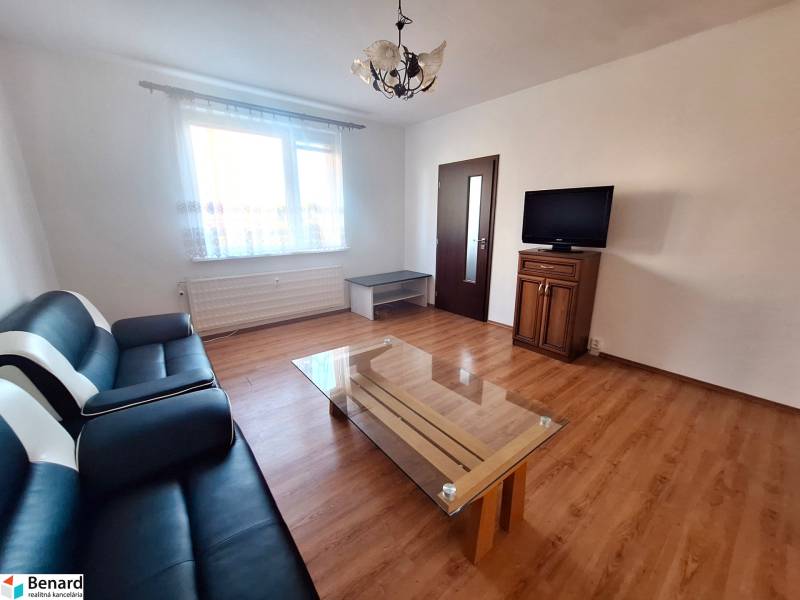 Living room with a sofa, table, and television, wooden decor flooring in a 3-room apartment.