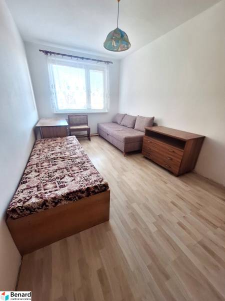 A room in a 3-room apartment with a wooden decor floor, an armchair, and a bed.