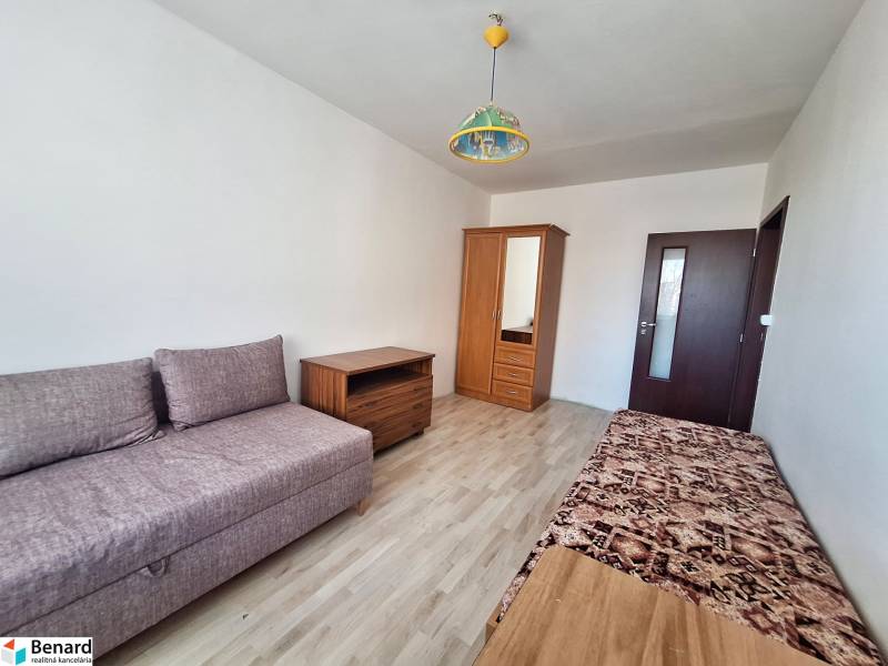 Living room in a 3-room apartment with a wooden decor floor and simple furniture.
