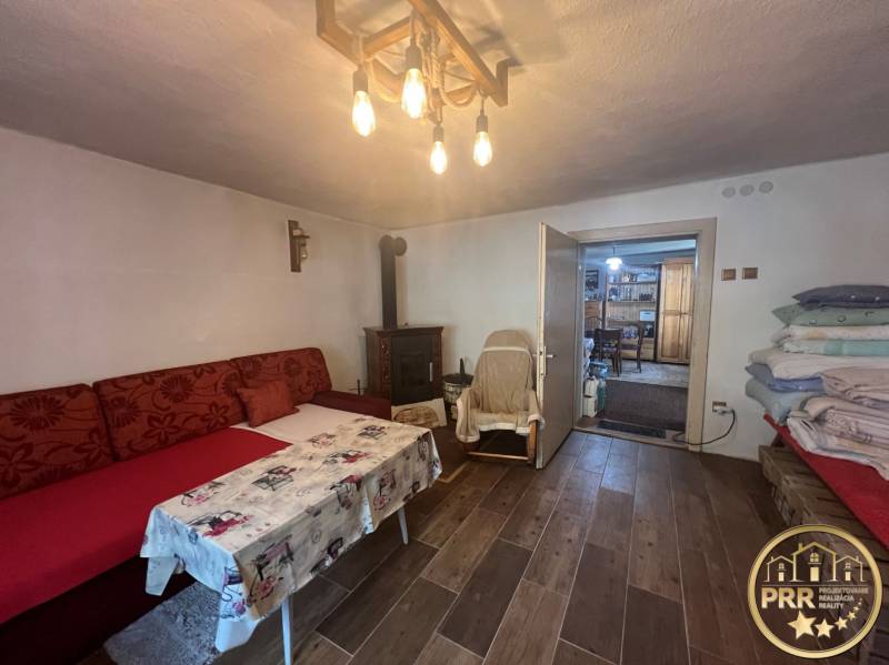 A comfortable room in a cabin with cozy seating, a fireplace, and a wooden ceiling.