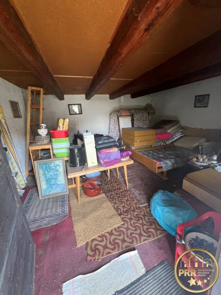 The interior of an unused cottage with rustic furniture and ceiling beams.