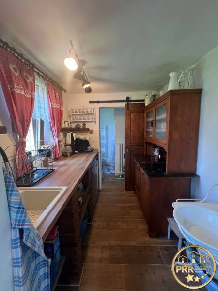 A kitchen in a wooden cabin with rustic furniture, a sink, and decorative curtains.