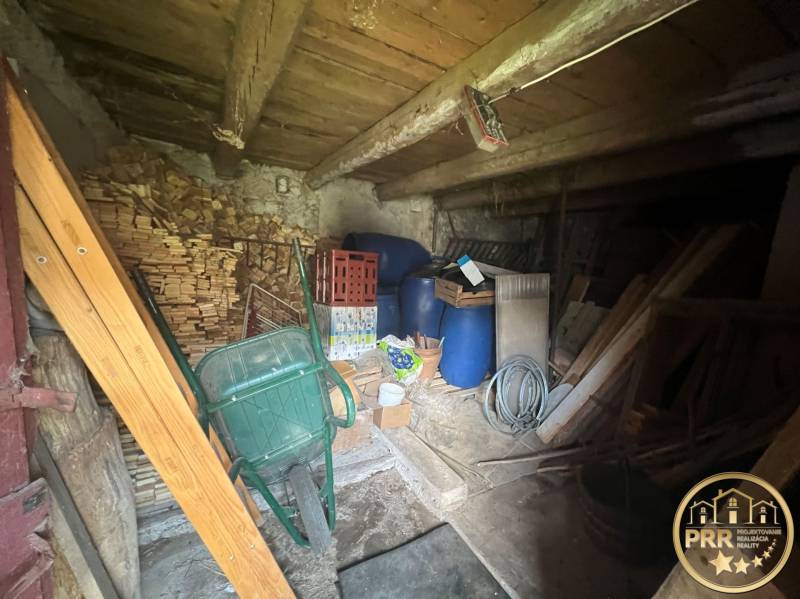 A wooden cabin with supplies of wood, barrels, and tools. A rustic attic suitable for storage.