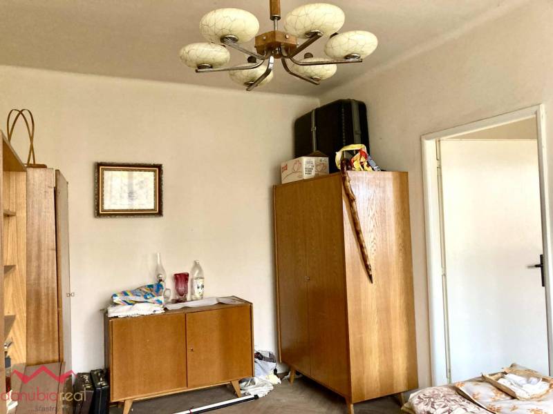 A room in a 3-room apartment with wooden furniture and a decorative chandelier.