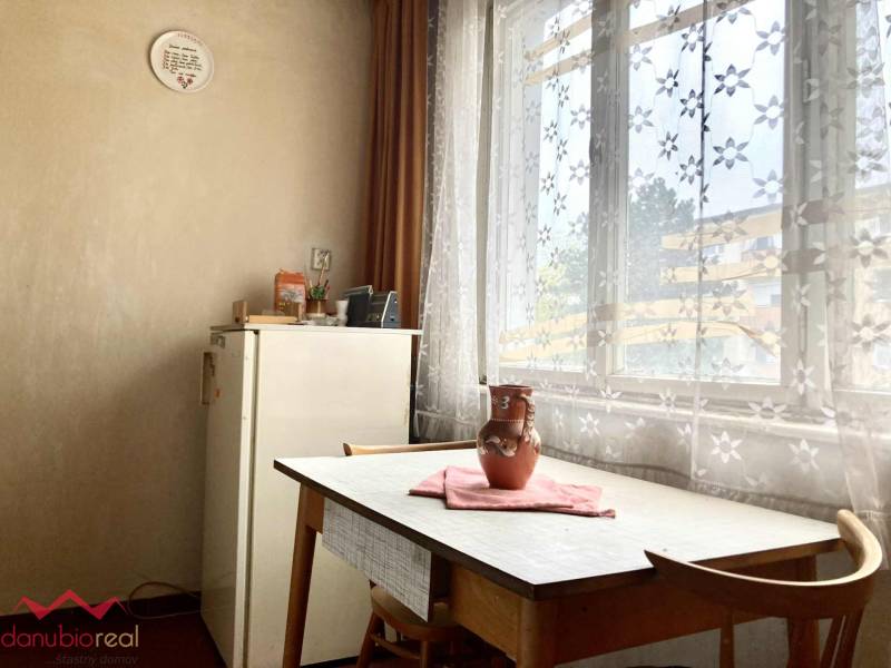 Dining room in a 3-room apartment with a table, chairs, and curtains with a floral pattern.