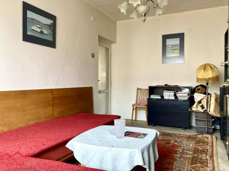 Living room in a 3-room apartment with a sofa, carpet, and decorative pictures on the wall.