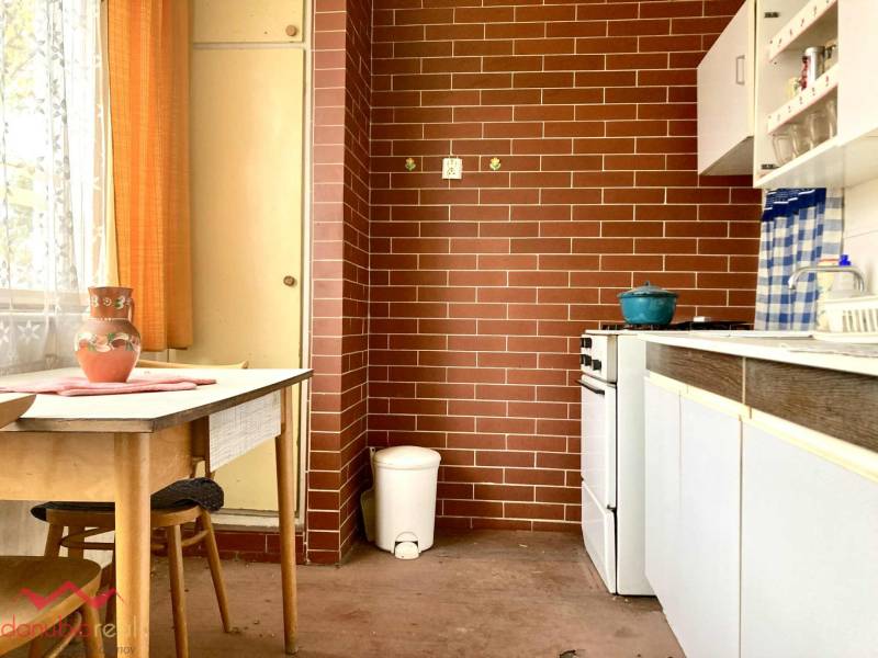 A kitchen in a 3-room apartment with red brick cladding and a wooden table.