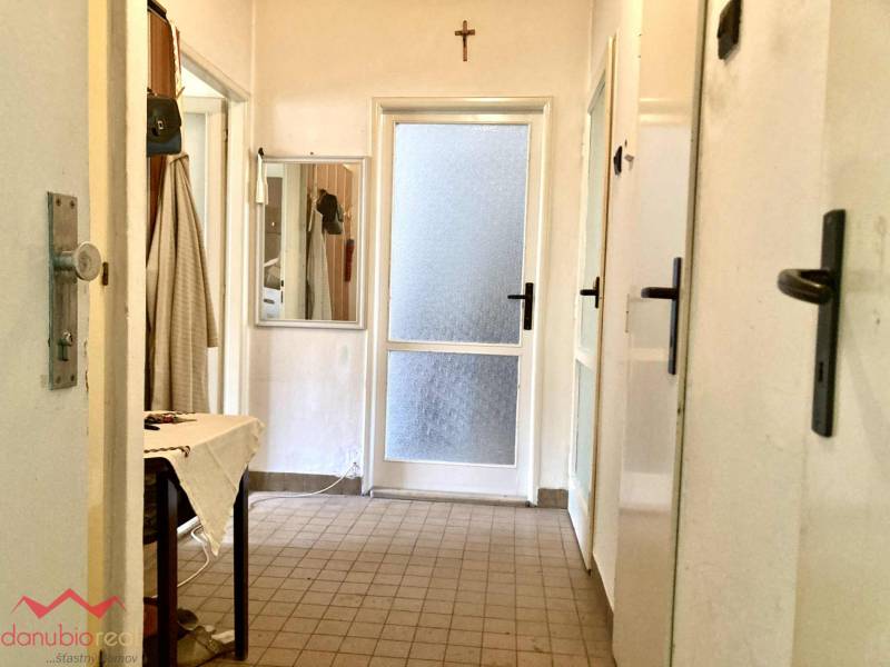 A hallway in a 3-room apartment with tiles, a mirror, and a canvas table.