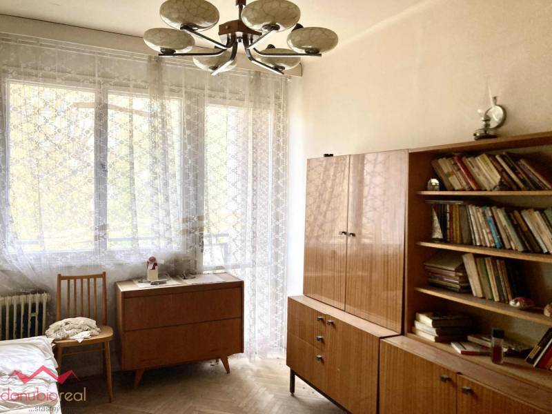 A room in a 3-room apartment with books, wooden furniture, and a floor with a wooden decor.