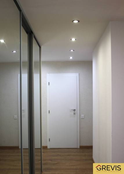 A hallway with a built-in mirrored wardrobe and a wooden decor floor in a 3-room apartment.