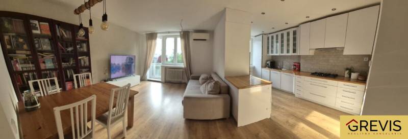 Spacious kitchen with living room in a 3-room apartment. Floor with wood decor, light furniture.