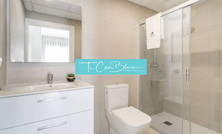 Bathroom of a holiday apartment with a toilet, sink, and shower.