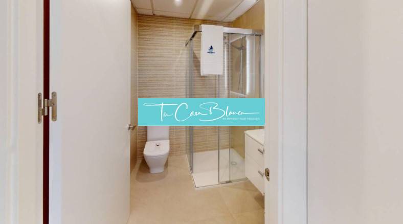 A bathroom in a holiday apartment with a toilet and a shower.