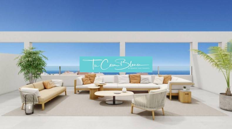 Terrace of a recreational apartment in Torrevieja with seating, ocean and blue sky in the background.