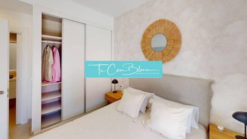 Bedroom in a holiday apartment with a bed, built-in wardrobe, and a mirror on the wall.