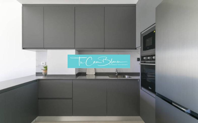 Kitchen in a holiday apartment with dark cabinets and built-in appliances.