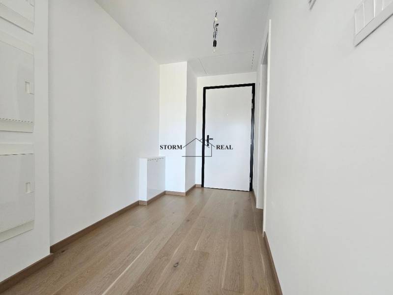 Hallway in a one-room apartment with white walls and a floor with a wood decor.