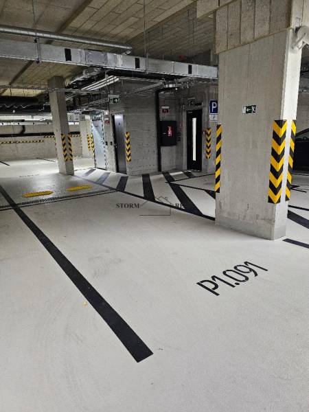 Underground parking lot with numbered spaces, security features, and lighting.