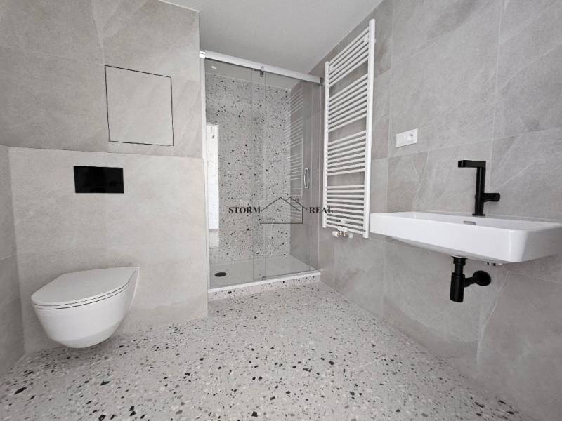 Bathroom with toilet, shower corner, and radiator in a studio apartment.