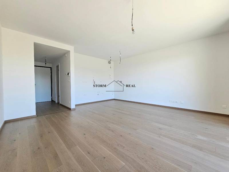 A spacious room with a wooden decor floor in a studio apartment.